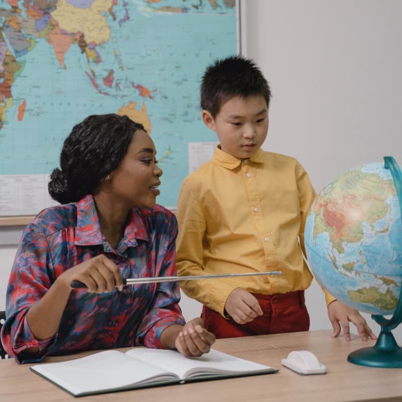A black woman teaching geography to an asian child.