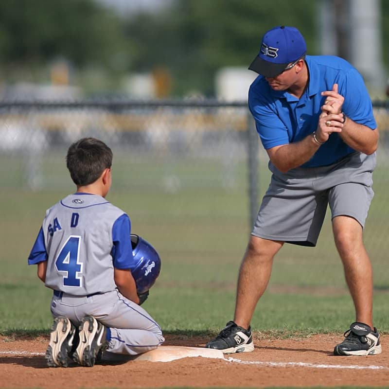 A softball coach coaching a player.