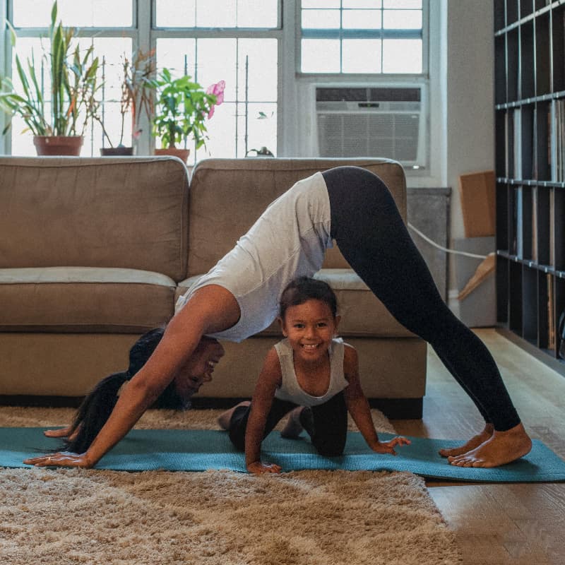 A mother daughter duo doing yoga at home.