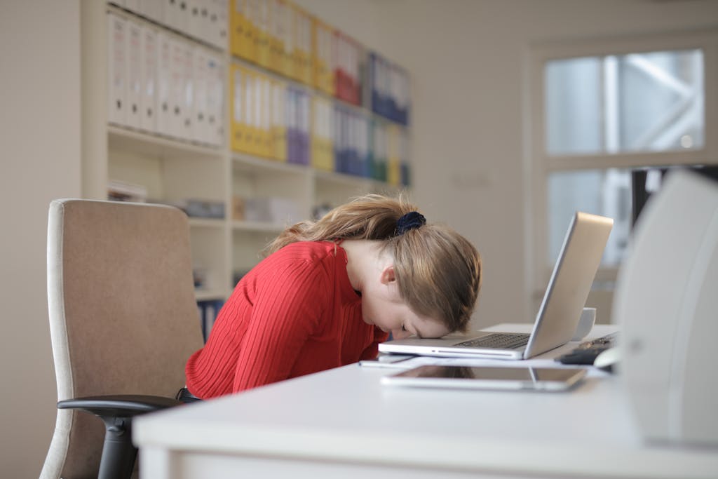 An exhausted teenager with her head on her desk