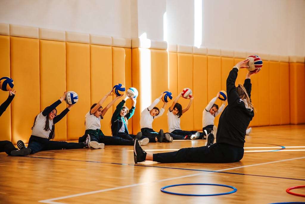 A coach with volleyball players in a wide angle yoga stretch