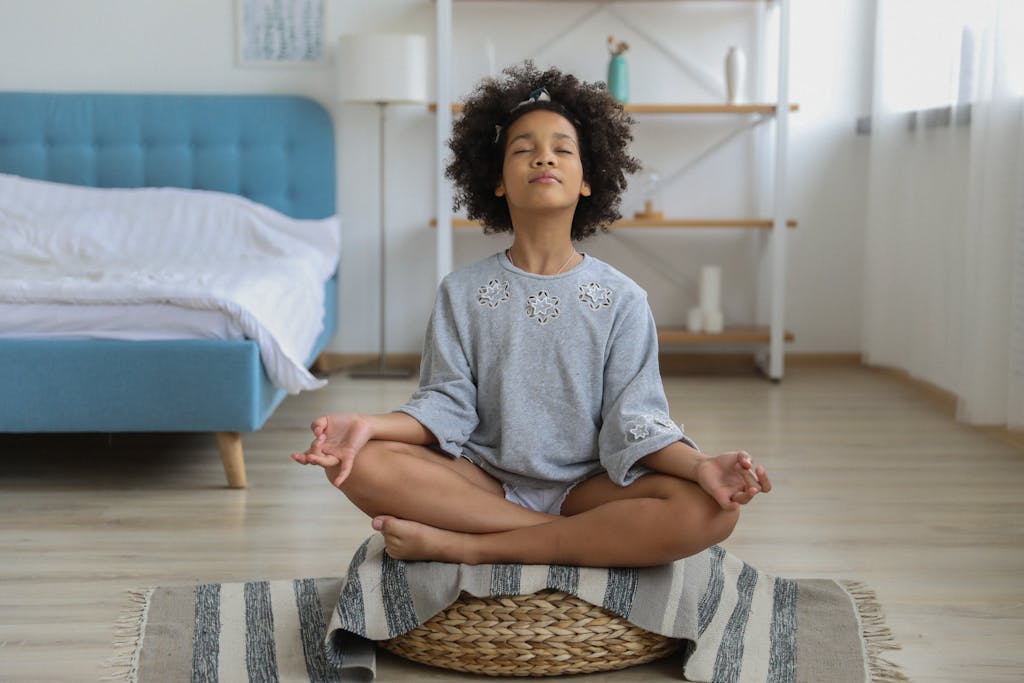 A preteen girl seated in a calm yoga pose