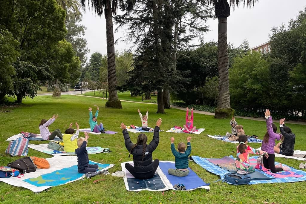 A circle of kids in yoga outdoors