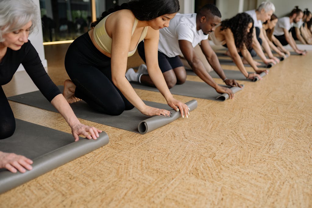 A row of adults rolling out their yoga mats
