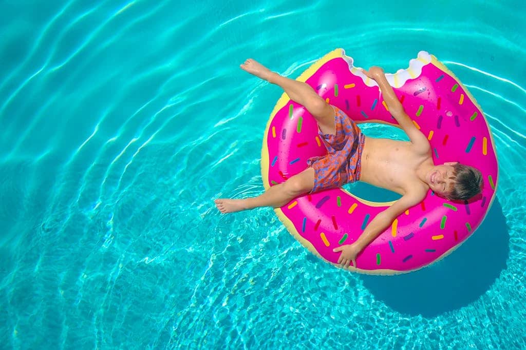 A boy in a pink donut floaty in the pool
