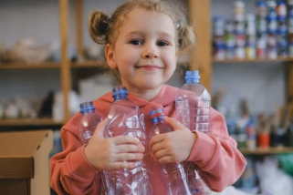 An adorable girl collecting empty plastic bottles for recycling...