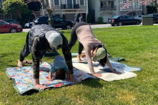 A father and his young son in a park doing yoga.